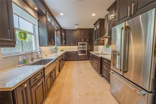 kitchen featuring a sink, decorative backsplash, dark brown cabinets, high end refrigerator, and black electric stovetop