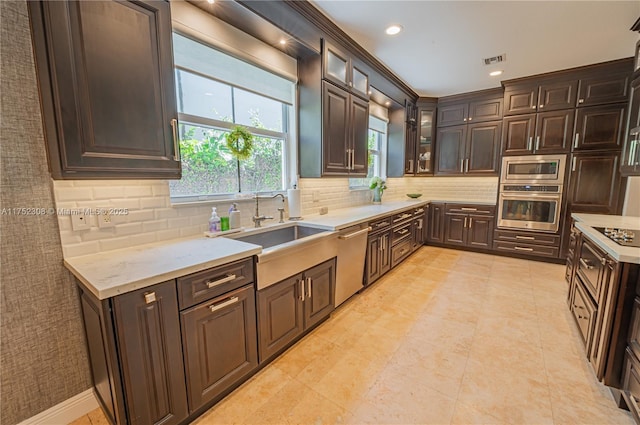 kitchen featuring visible vents, backsplash, dark brown cabinets, stainless steel appliances, and a sink