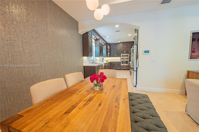 dining space featuring recessed lighting, arched walkways, light tile patterned floors, baseboards, and an accent wall