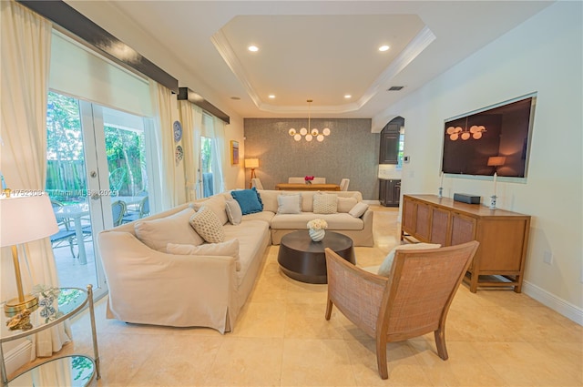 living area with baseboards, recessed lighting, an inviting chandelier, arched walkways, and a raised ceiling