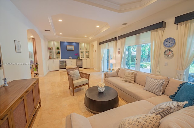 living area with built in features, a tray ceiling, arched walkways, and wine cooler