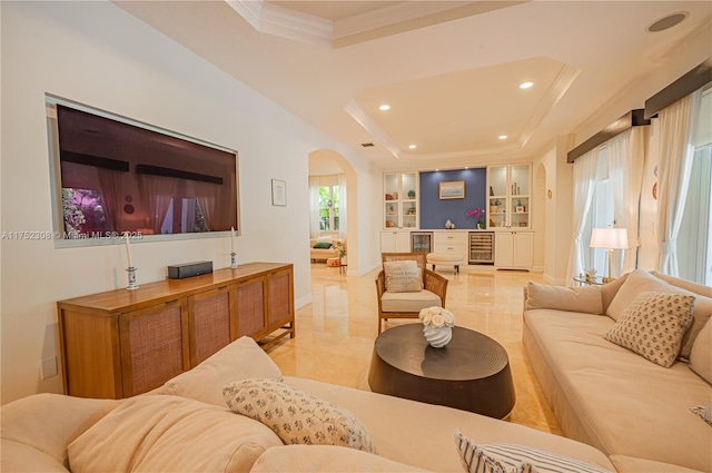 living area with built in shelves, a tray ceiling, arched walkways, ornamental molding, and wine cooler