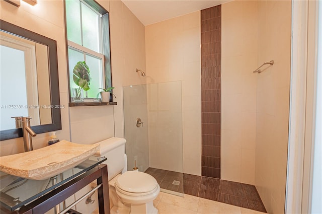 full bathroom with tile patterned flooring, toilet, vanity, and a tile shower