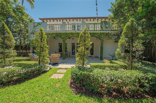 back of house with stucco siding, fence, a balcony, ceiling fan, and a patio area