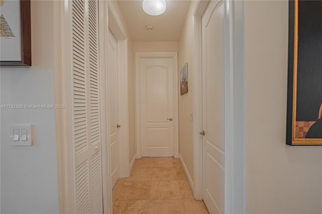 hallway featuring light tile patterned floors and baseboards