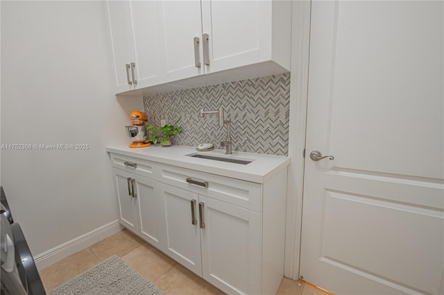 interior space with a sink, baseboards, cabinet space, and light tile patterned flooring