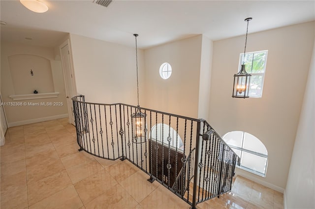 corridor featuring baseboards, an upstairs landing, an inviting chandelier, and visible vents