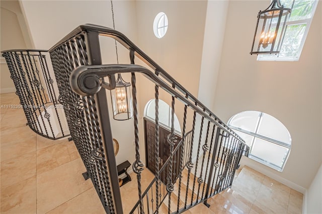 stairway with a chandelier, tile patterned floors, and baseboards