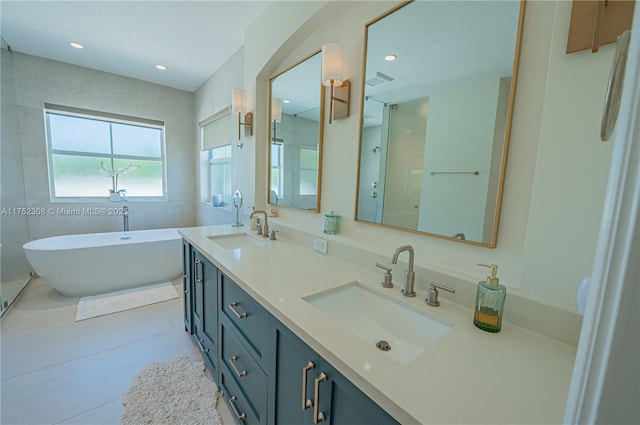 full bathroom featuring a freestanding bath, tile patterned floors, recessed lighting, and a sink