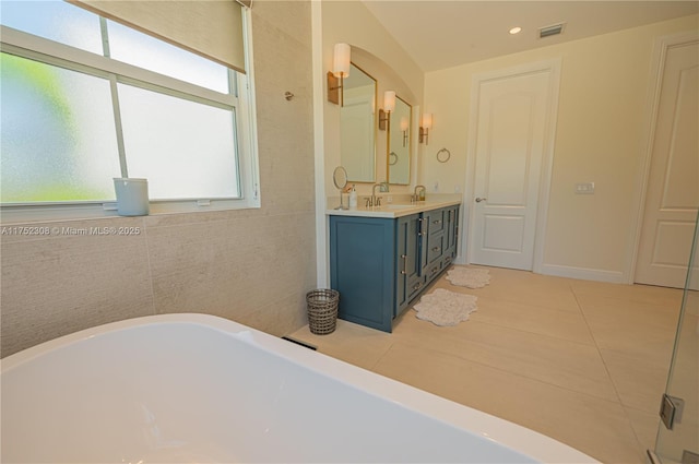 full bath featuring double vanity, a freestanding tub, visible vents, and tile patterned floors