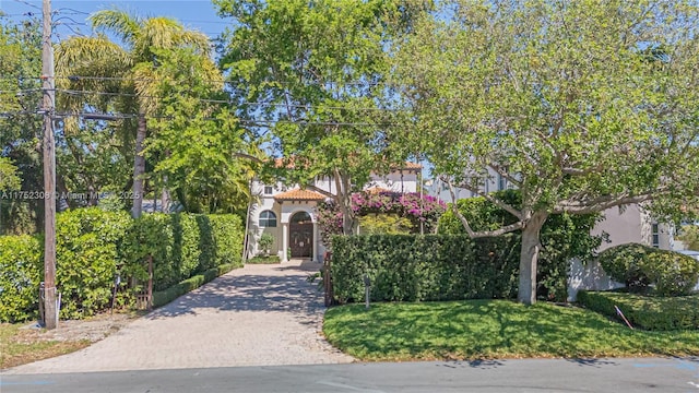 view of front of property with a front yard, decorative driveway, a tile roof, and stucco siding