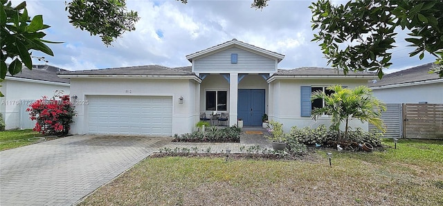 single story home featuring a front lawn, fence, stucco siding, decorative driveway, and an attached garage