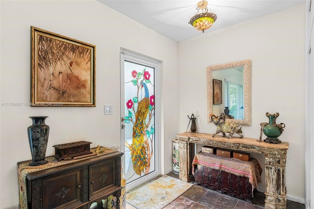 foyer featuring baseboards and stone finish floor