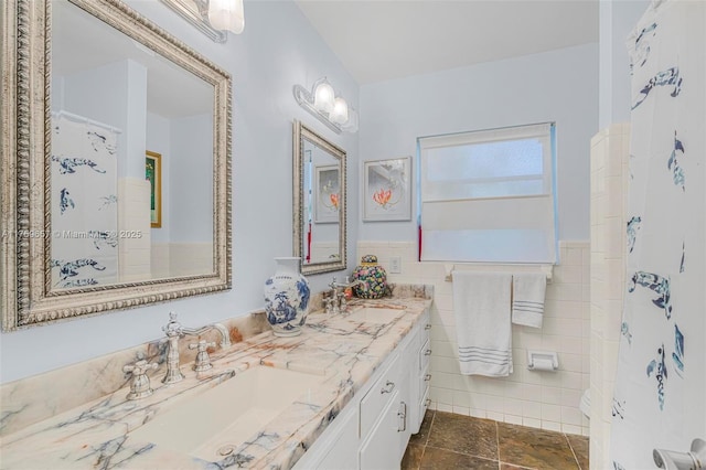 full bath featuring a sink, a wainscoted wall, tile walls, and double vanity