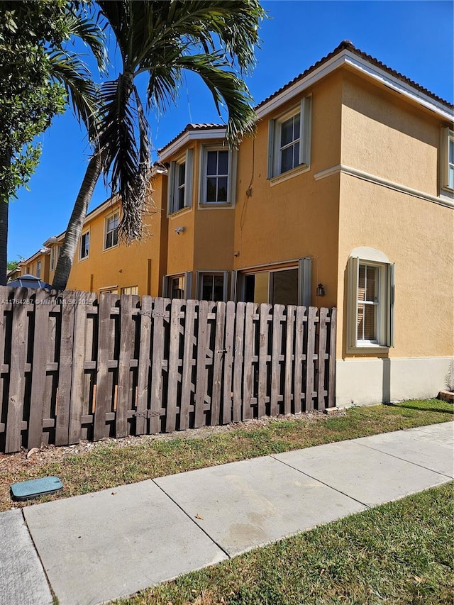 view of front of house with a tiled roof, a fenced front yard, and stucco siding