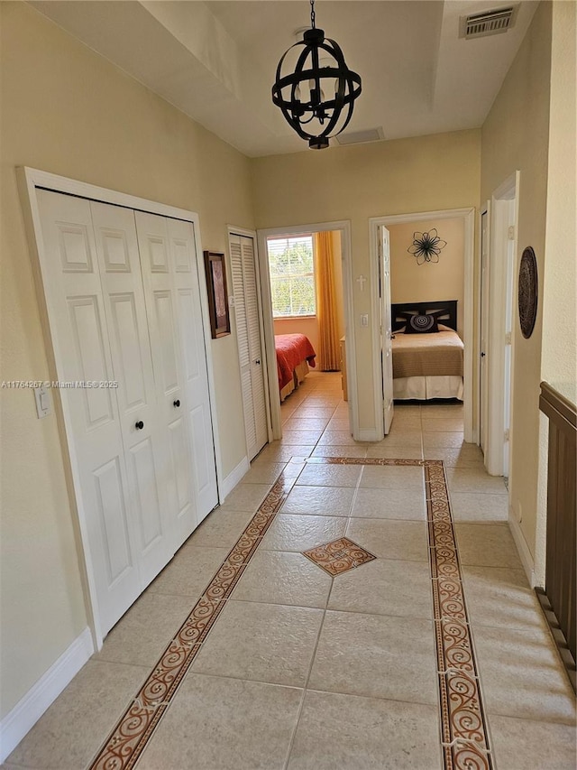 corridor with visible vents, baseboards, and an inviting chandelier