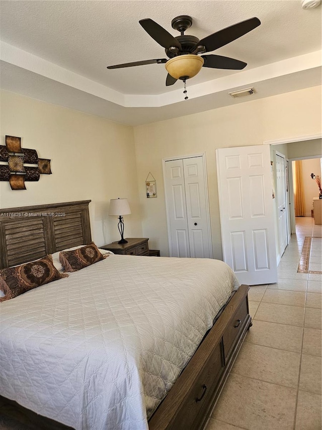 bedroom with light tile patterned flooring, visible vents, a textured ceiling, and ceiling fan