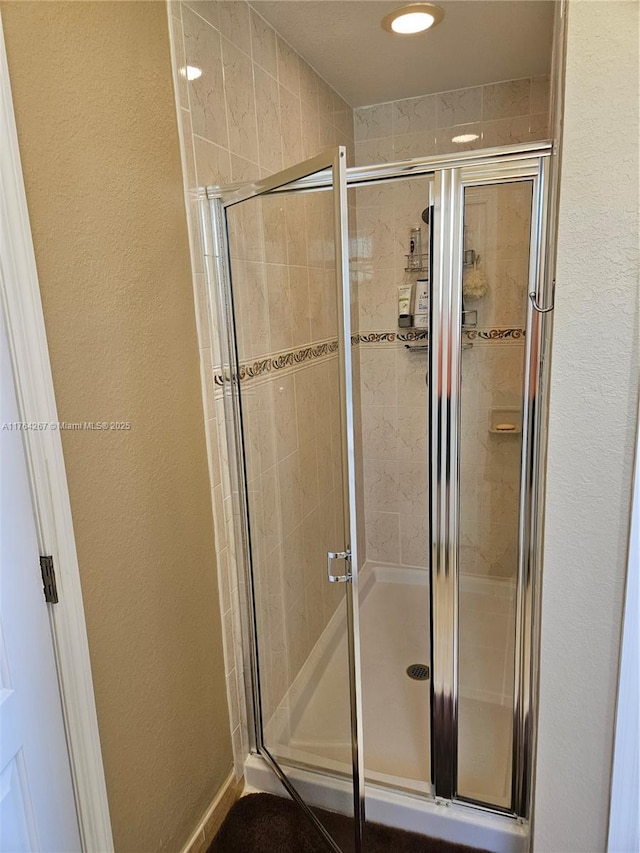 full bath featuring a shower stall and a textured wall