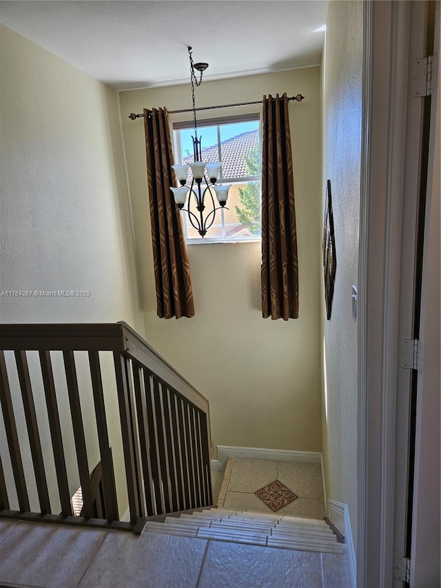 stairway featuring baseboards and a chandelier