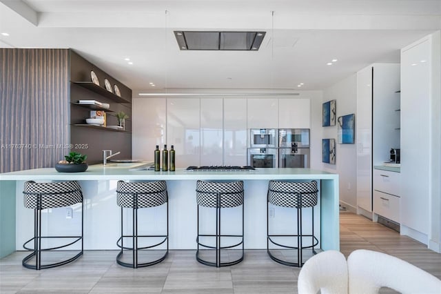 4701 N Meridian Ave Unit 603, Miami Beach, FL 33140 - kitchen featuring open shelves, light countertops, a peninsula, white cabinetry, and modern cabinets