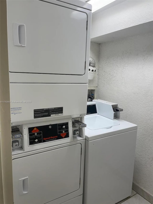 common laundry area featuring stacked washer and dryer, washing machine and dryer, and a textured wall