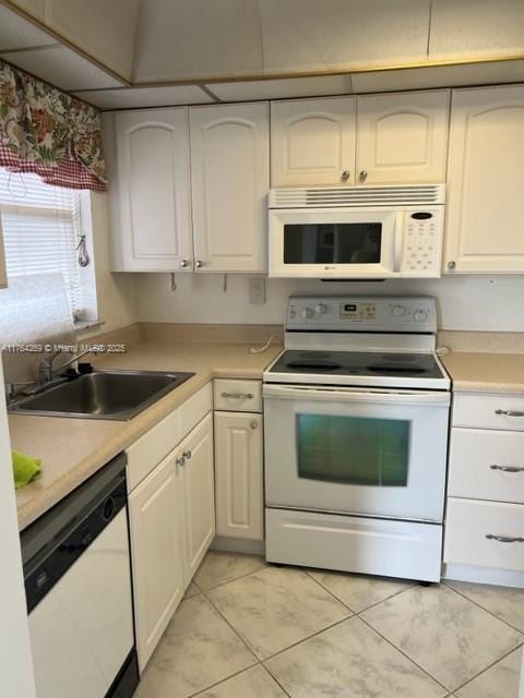 kitchen with a sink, white appliances, white cabinetry, and light countertops