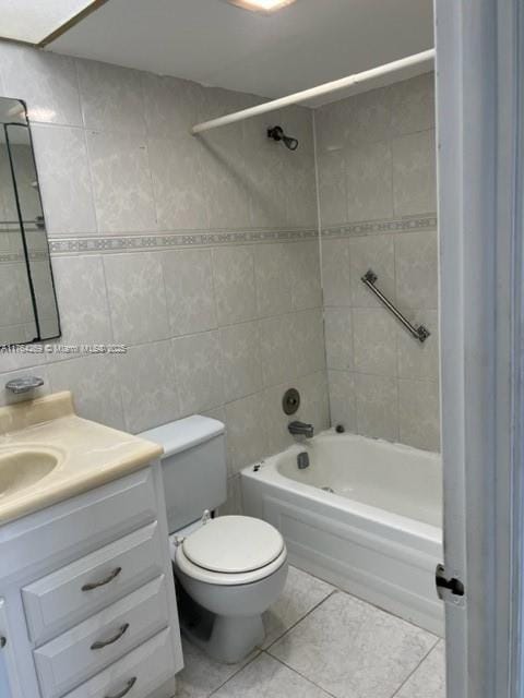 bathroom featuring tile patterned flooring, vanity, bathing tub / shower combination, and tile walls