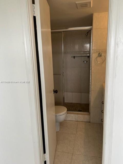 bathroom with tile patterned flooring, a shower stall, toilet, and visible vents