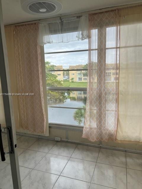 interior space featuring light tile patterned floors and a water view