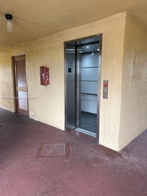 view of exterior entry featuring stucco siding and elevator