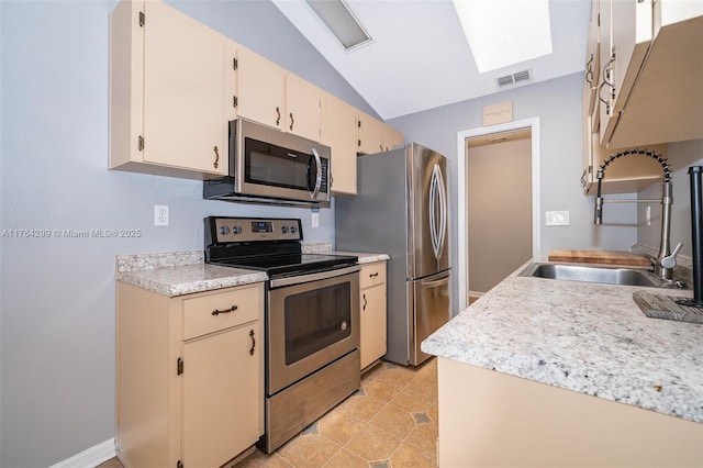 kitchen with visible vents, vaulted ceiling with skylight, a sink, stainless steel appliances, and light countertops