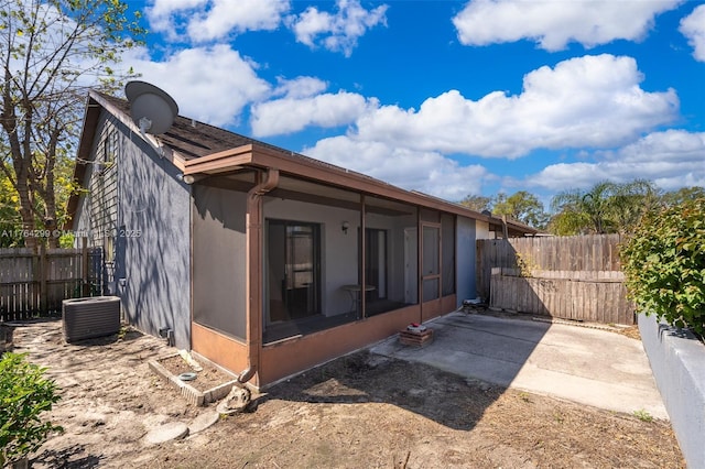 back of house with stucco siding, central AC, a fenced backyard, and a sunroom