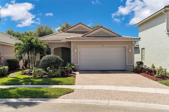 view of front of house featuring a tile roof, decorative driveway, an attached garage, and stucco siding