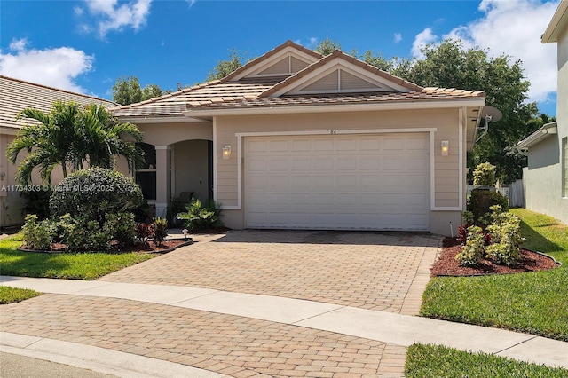 single story home featuring a tile roof, decorative driveway, and a garage