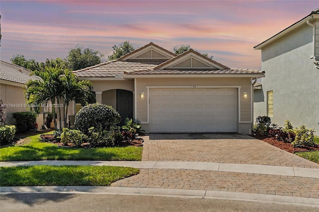 view of front of property with a garage, stucco siding, driveway, and a tiled roof