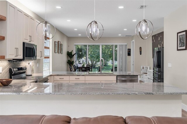 84 Belle Grove Ln, Royal Palm Beach, FL 33411 - kitchen with stainless steel appliances, a sink, a peninsula, recessed lighting, and light stone counters