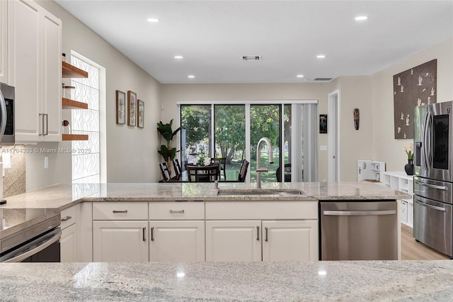 kitchen featuring a sink, light stone countertops, appliances with stainless steel finishes, and white cabinetry