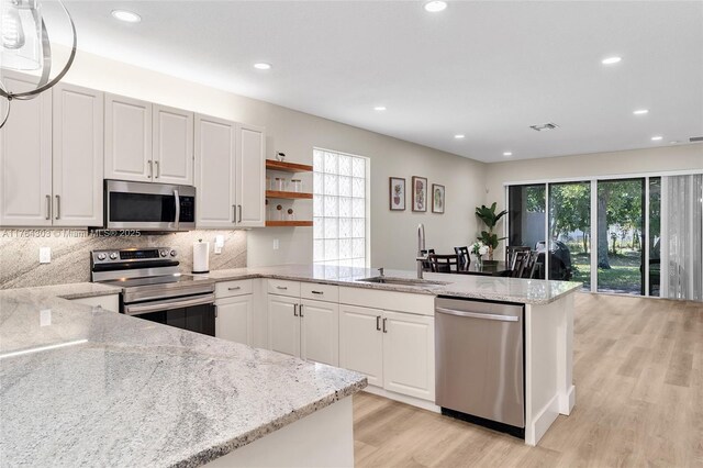 84 Belle Grove Ln, Royal Palm Beach, FL 33411 - kitchen with appliances with stainless steel finishes, a sink, a peninsula, light wood finished floors, and recessed lighting