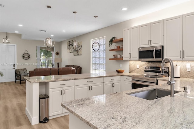 kitchen with open shelves, tasteful backsplash, white cabinetry, appliances with stainless steel finishes, and a peninsula