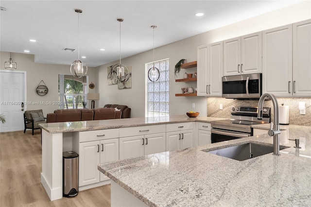 84 Belle Grove Ln, Royal Palm Beach, FL 33411 - kitchen with appliances with stainless steel finishes, a peninsula, a sink, open shelves, and light wood-style flooring