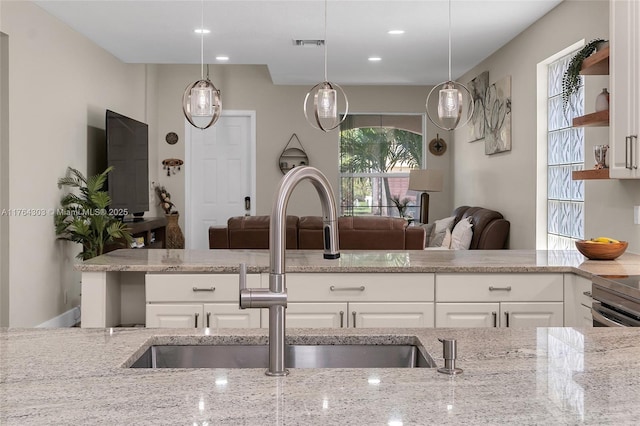 kitchen with visible vents, light stone countertops, and a sink