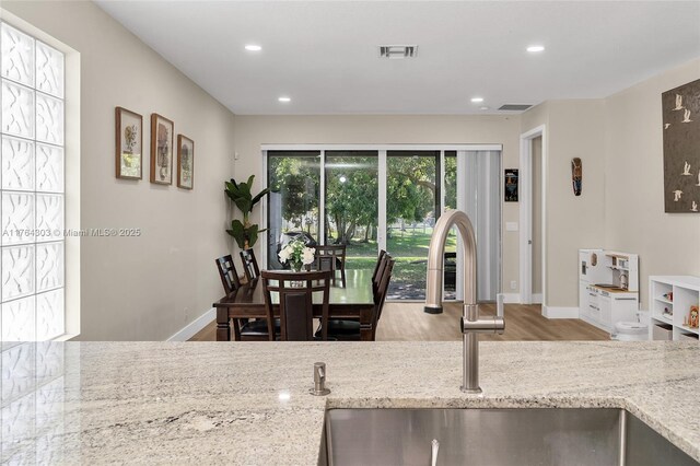 84 Belle Grove Ln, Royal Palm Beach, FL 33411 - kitchen with a sink, wood finished floors, light stone counters, baseboards, and recessed lighting