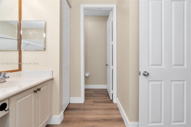 bathroom with baseboards, wood finished floors, and vanity