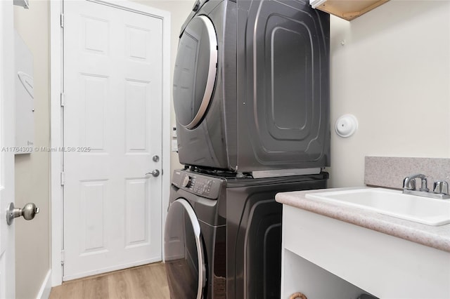 laundry area with laundry area, light wood finished floors, and stacked washing maching and dryer