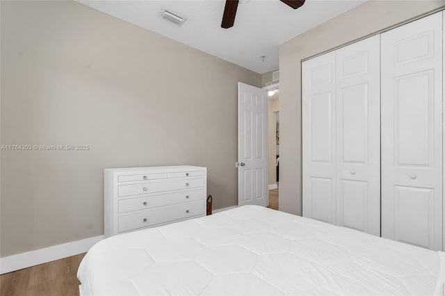 bedroom with wood finished floors, visible vents, baseboards, ceiling fan, and a closet