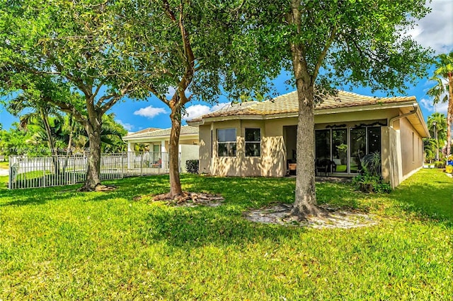 back of property with fence, a lawn, and stucco siding