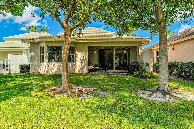 rear view of property featuring stucco siding and a yard