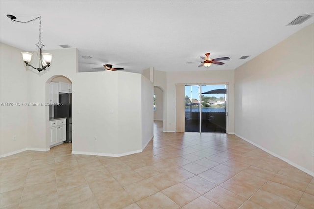 empty room with visible vents, ceiling fan with notable chandelier, and arched walkways