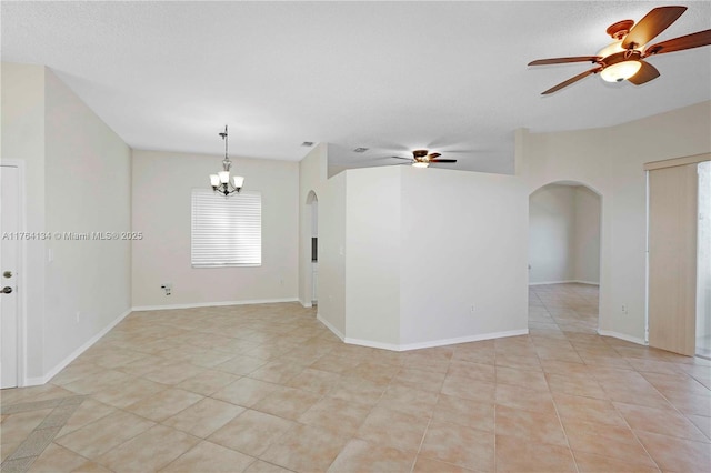 unfurnished room featuring arched walkways, ceiling fan with notable chandelier, baseboards, and light tile patterned flooring