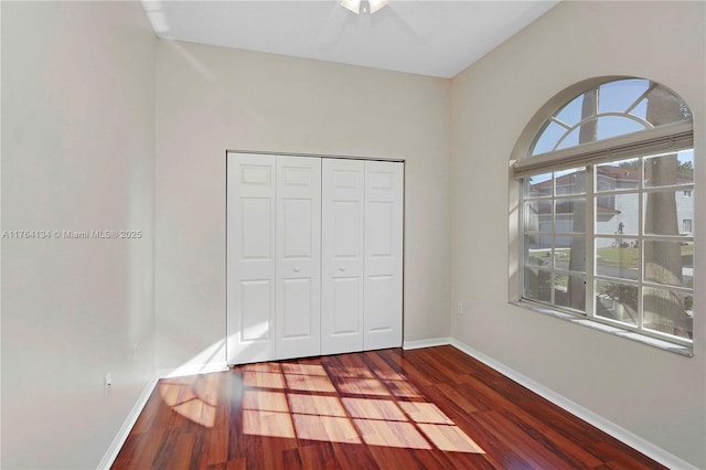 unfurnished bedroom with a closet, baseboards, and wood finished floors